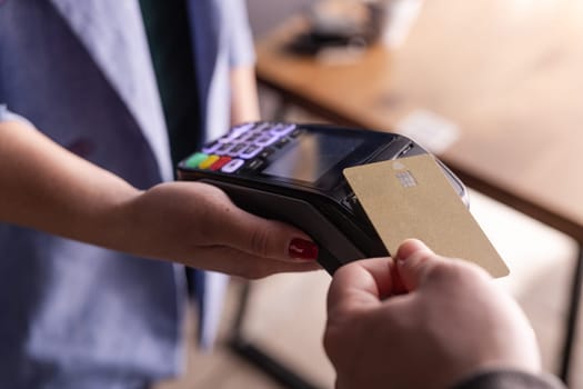NFC credit card payment. Woman paying with contactless credit card with NFC technology. Wireless money transaction. Card machine in male hand on sunlight background