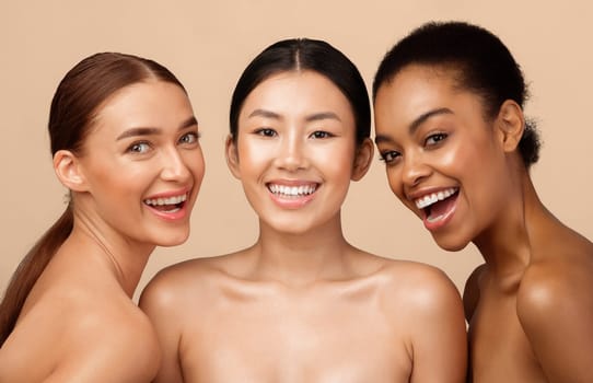 Three Joyful Models Girls Posing Smiling To Camera Standing Shirtless On Gray Background. Studio Shot. Natural Beauty Concept