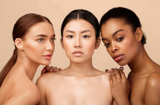 Three Beautiful Multiethnic Models Girls Posing Shirtless Over Gray Background In Studio. Female Beauty Group Portrait