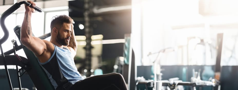 Healthy lifestyle and sport concept. Young man exercising with training apparatus in gym, empty space