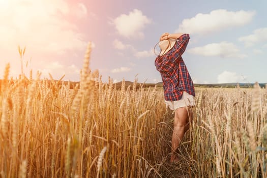 Woman farmer walks through a wheat field at sunset, touching green ears of wheat with his hands. Hand farmer is touching ears of wheat on field in sun, inspecting her harvest. Agricultural business.