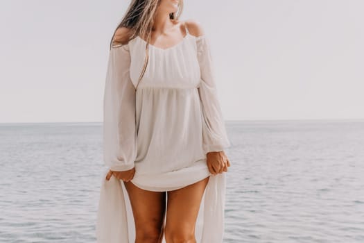 Woman travel sea. Young Happy woman in a long red dress posing on a beach near the sea on background of volcanic rocks, like in Iceland, sharing travel adventure journey