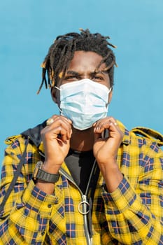 vertical photo of an attractive young black man wearing a protective mask, lifestyle concept and virus protection