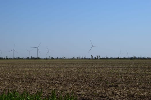 A field of windmills spin in front of a colorful evening sky. A wind turbine is used to produce electricity. Wind energy is the use of wind for electrical power. It's a sustainable, renewable energy