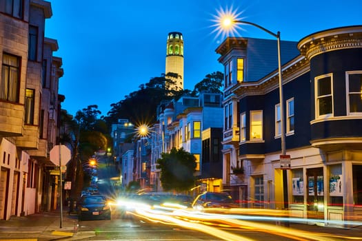 Image of Coit Tower at night from California street with blurred car lights and bright city lights
