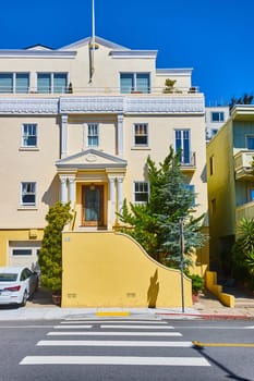 Image of Light yellow houses on city street on clear blue sky day