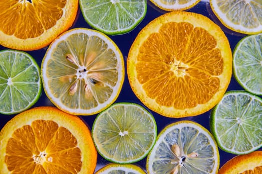 Image of Slices of lemons and limes with oranges on navy blue background