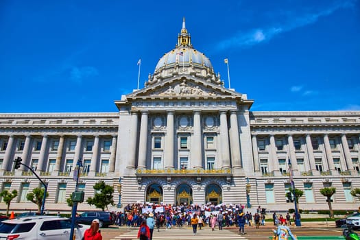 Image of Protestors with signs gathering in front of government building city hall on bright summer day