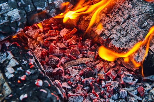 Image of Macro view glowing red embers with yellow and orange flames background asset