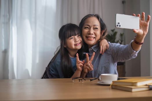 Grandma and granddaughter happily sit and play together in the living room..