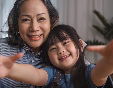 Grandma and granddaughter happily sit and play together in the living room..