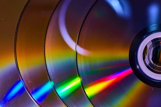 Image of Abstract stack of four CDs with reflective rainbow cones of light