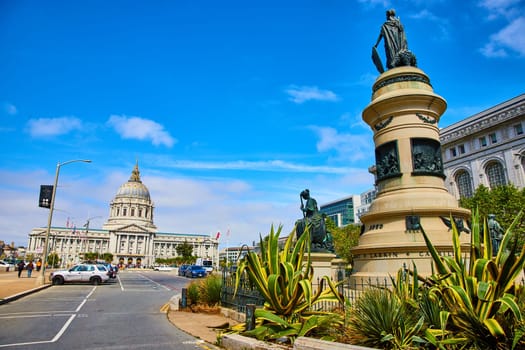 Image of Backside of Pioneer Monument with distant city hall on blue sky day with purple tinged clouds