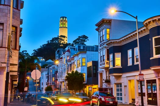 Image of Nighttime view of California street lit up with blurred cars and glowing Coit Tower