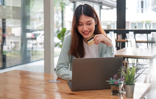 Asian woman using laptop computer and credit card for shopping online.