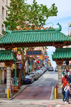 Image of Pedestrians and cars around iconic San Francisco Chinatown entrance with green tree behind it