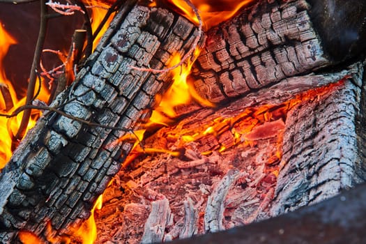 Image of Ash covered logs with yellow and orange flames close up background asset