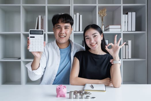 Asian couples are calculating their expenses with a calculator. They are happy..