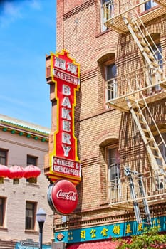Image of Large sign for bakery on side of tan brick building with light yellow fire escape ladders