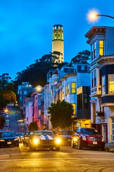 Image of Nighttime view of California street with blurred cars and glowing Coit Tower