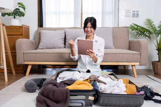 A young female tourist is feeling happy from her upcoming trip and is preparing to pack her things for the trip..