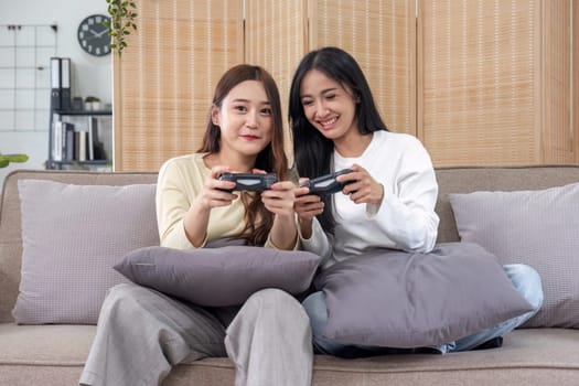 Young Asian couple playing video games at home in the living room having fun..