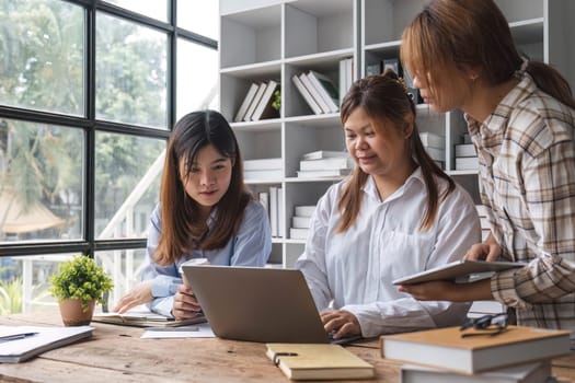 Asian College groups of students using laptop, tablet, studying together with notebooks documents paper for report near windows in classroom. Happy young study for school assignment