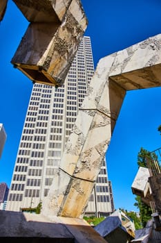 Image of Tall abstract sculpture of Vaillancourt Fountain with tall skyscraper behind it on blue sky day