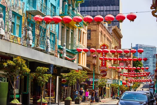 Image of Chinatown in San Francisco with red paper lanterns over street with pedestrians and wall art