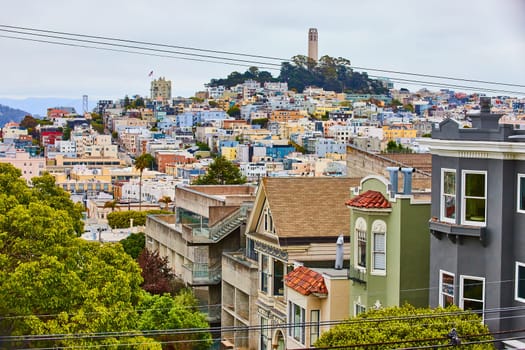 Image of Close up of colorful buildings with telephone wires leading to Coit Tower in distance