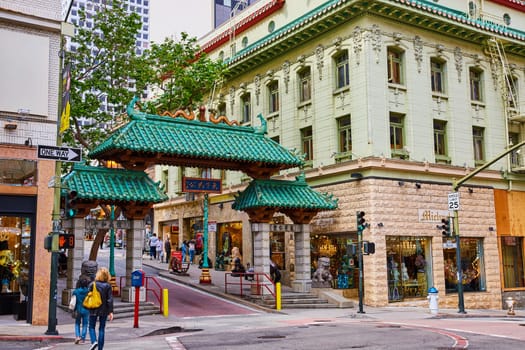 Image of Iconic Chinatown entrance with green tree behind it and stone lions off to side