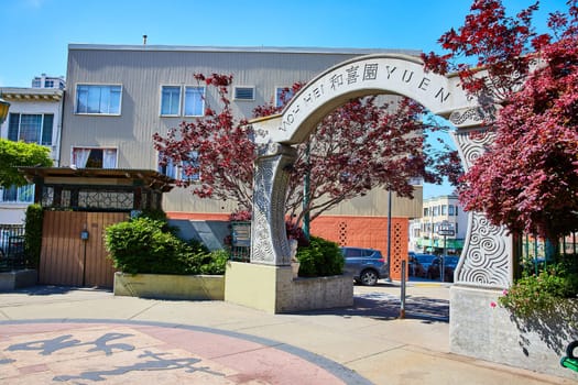 Image of Partial moon gate entrance into Who Hei Yuen park in Chinatown framed by Japanese maple trees