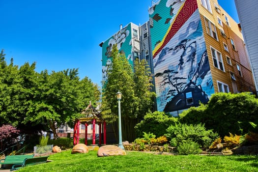 Image of Zen park with building mural of white flowers and mountain view of bonsai trees in the clouds