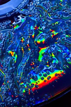 Image of Oily surface with rainbow burst of color and frothy bubbles in abstract background asset