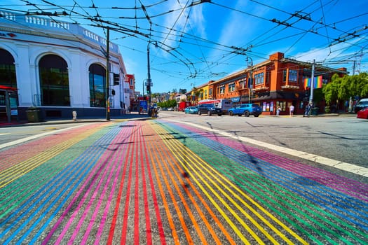 Image of Castro District rainbow crosswalk with store fronts and brilliant blue skies