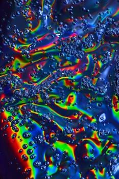 Image of Abstract art of watery goo with bubbles foaming across colorful oily surface background asset