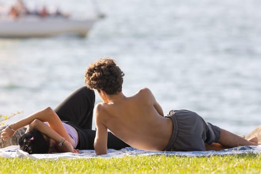 Young couple having a rest on the cliff by the sea. Mid shot