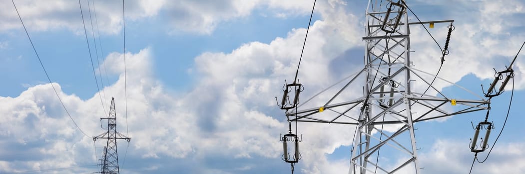 The sky strewn with white clouds in a shot of a narrow panoramic frame with high voltage line poles on it. Energy management.