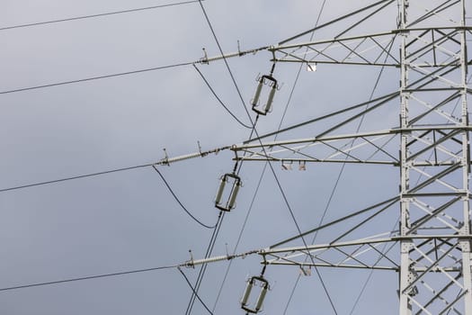 Fragment of a high voltage electric pole. Close-up of electrical insulators at high voltages of an overhead line.