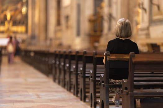 A woman sits in a church. Mid shot