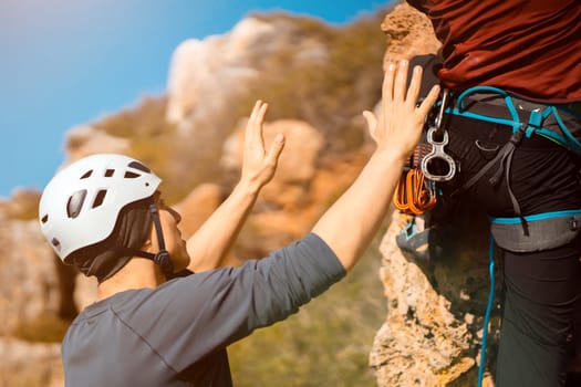 Two men are engaged in mountaineering, rock climbing on a sunny day in the mountains with climbing equipment, with ropes, carabiners, in helmets. 2 People lead an active life style.