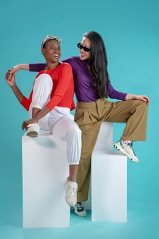 Two attractive women pose on blue background. High quality photo