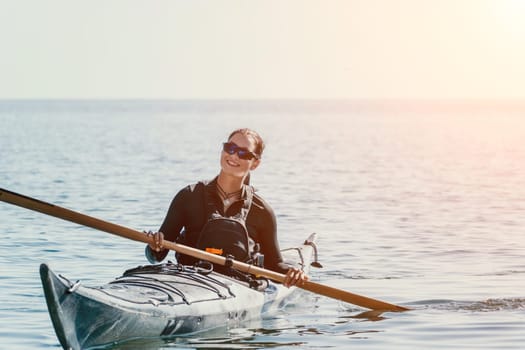 Happy smiling woman in kayak on ocean, paddling with wooden oar. Calm sea water and horizon in background