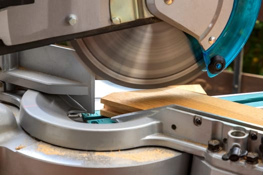 Miter saw in the process of sawing off a wooden part. Close up