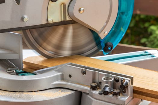 Miter saw in the process of sawing off a wooden part. Close up