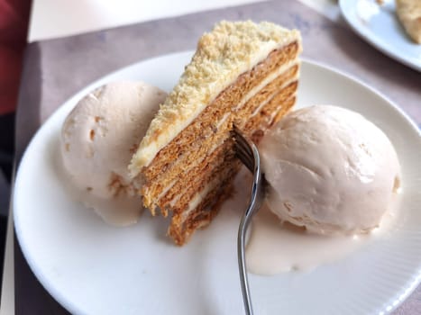 Close up of a delicate piece of cake and ice cream,on a plate with a fork