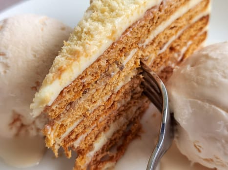 Close up of a delicate piece of cake and ice cream,on a plate with a fork