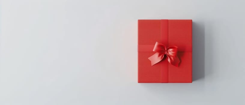 A vibrant red gift box with a satin ribbon lies on a textured white surface, evoking feelings of anticipation and celebration