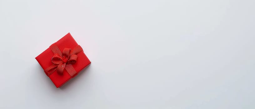 A minimalist red gift box with a neatly tied bow stands out on a pristine white background, symbolizing elegance and thoughtful giving. Its crisp presentation suggests a modern twist to gift-giving
