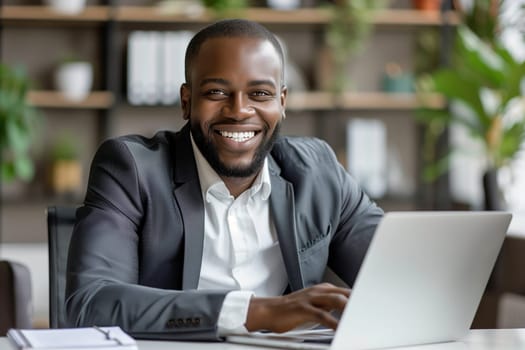 Happy successful African young businessman working on a laptop, smiling black male entrepreneur sitting in a cafe